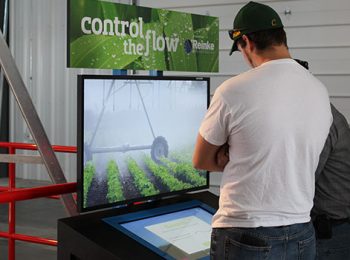 Man in front of a large display watching a movie about watering farmland.